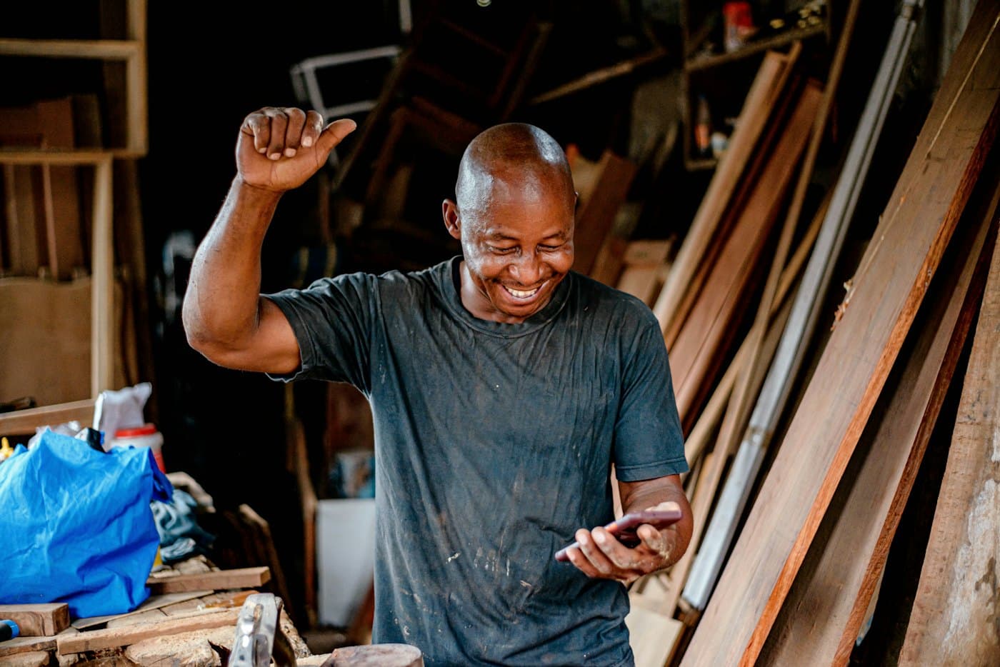 A carpenter checking his phone in his workshop