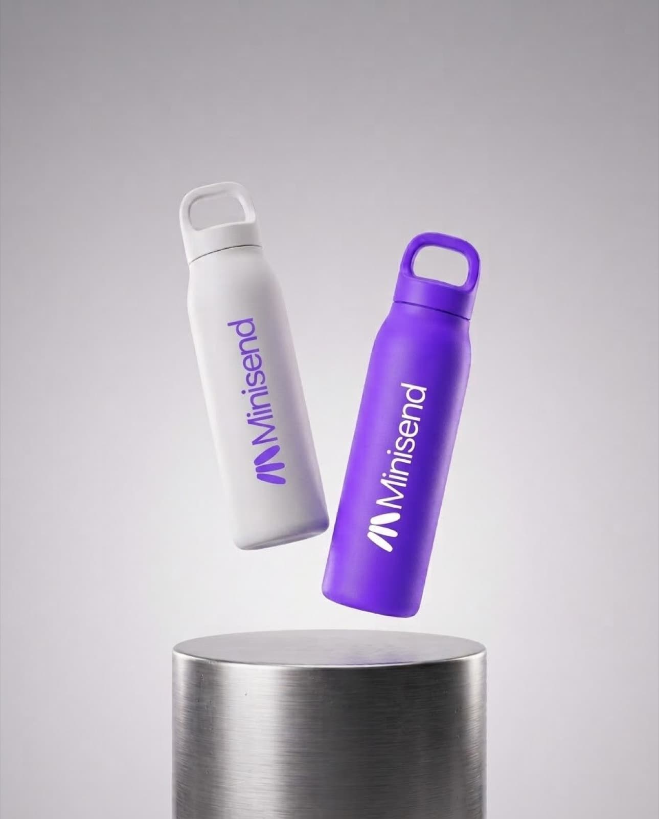 A purple and a white Minisend bottle floating above a steel plinth