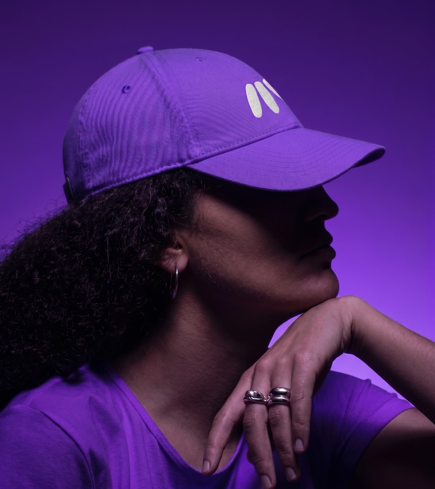 Woman in profile under purple light, wearing the purple Mark cap