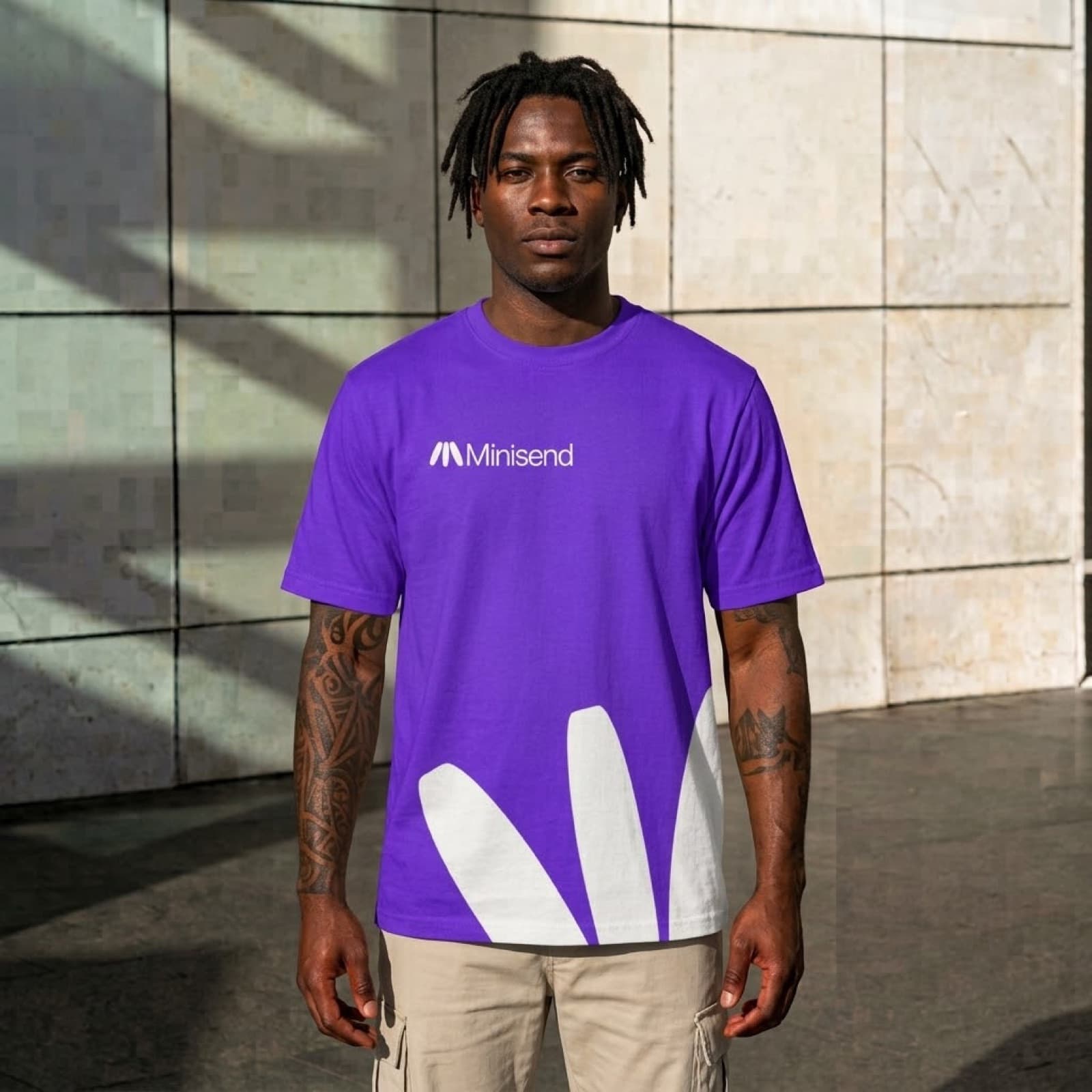 Man standing in afternoon light outside, wearing the purple Mark tee