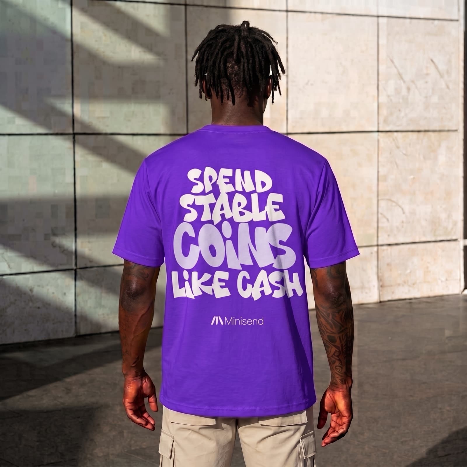 Man seen from behind outside, wearing the purple tee with the slogan across his back